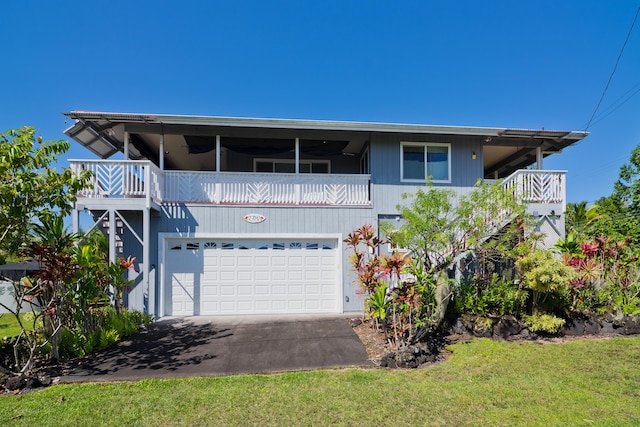 view of front of property featuring a front yard, a balcony, and a garage