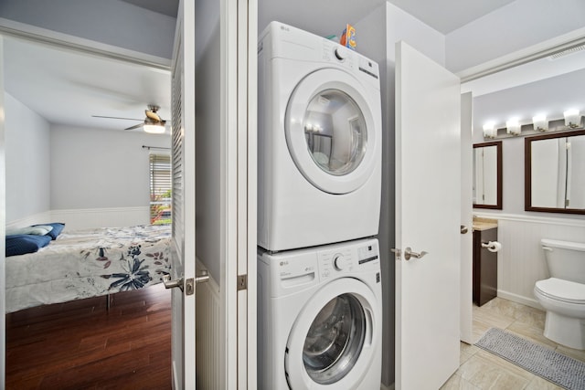 washroom with light tile patterned floors, stacked washer / dryer, and ceiling fan