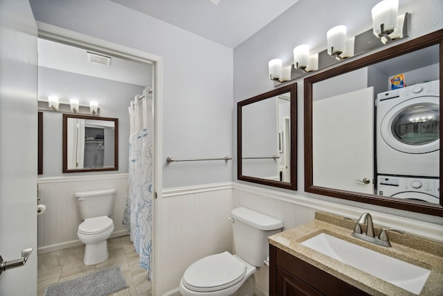 bathroom with tile patterned floors, stacked washer and dryer, vanity, and toilet