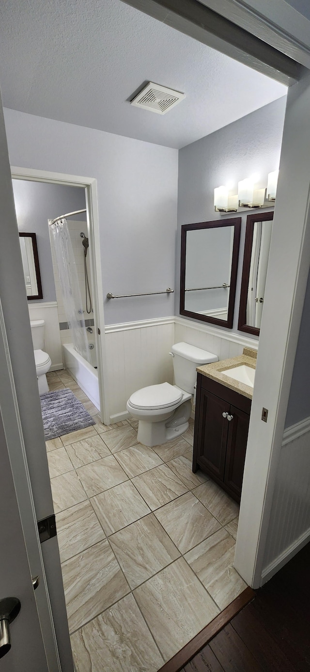 full bathroom featuring vanity, shower / bath combination with curtain, a textured ceiling, and toilet