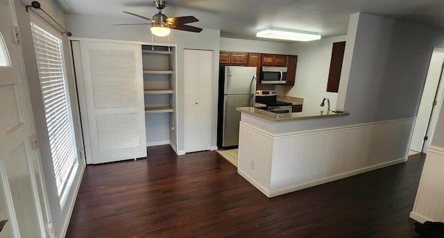 kitchen with kitchen peninsula, stainless steel appliances, ceiling fan, sink, and dark hardwood / wood-style floors