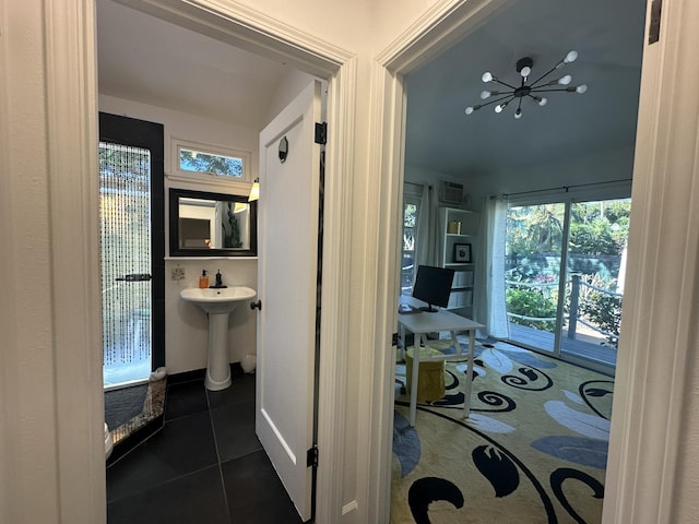 corridor with dark tile patterned flooring, sink, and an inviting chandelier