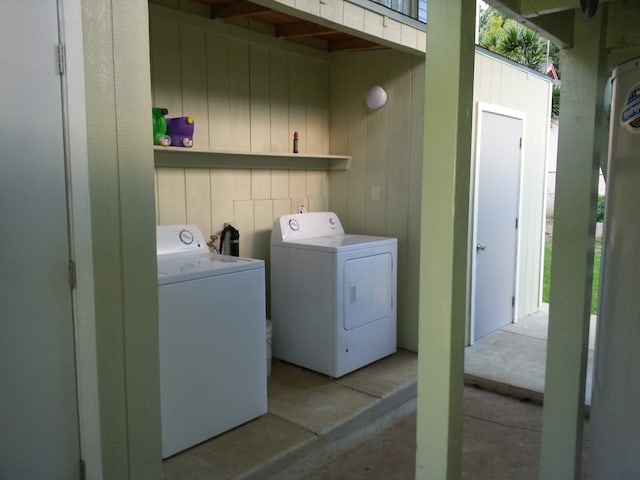 clothes washing area with washing machine and dryer and wooden walls