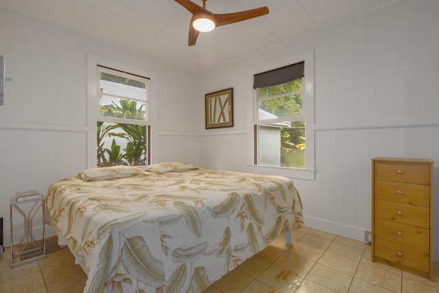 bedroom with ceiling fan, light tile patterned floors, and multiple windows