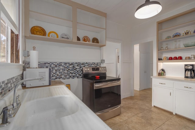 kitchen with stainless steel electric stove, white cabinets, sink, decorative backsplash, and light tile patterned floors