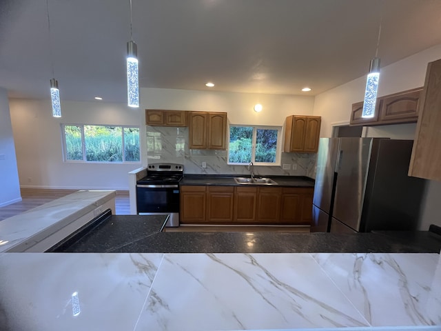 kitchen with stainless steel appliances, decorative light fixtures, sink, and tasteful backsplash