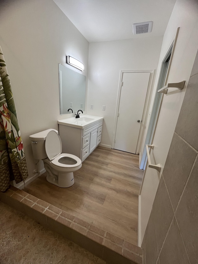 bathroom featuring toilet, hardwood / wood-style flooring, curtained shower, and vanity