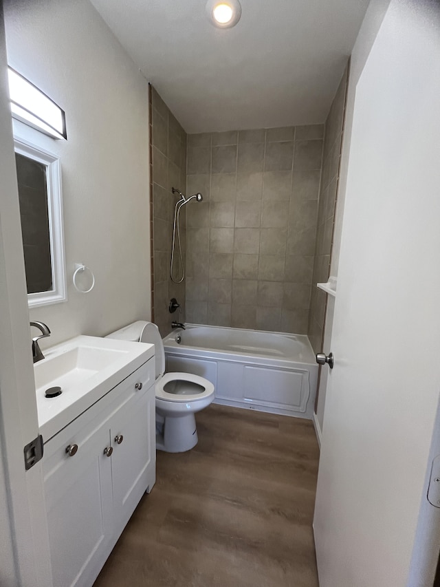 full bathroom featuring toilet, wood-type flooring, vanity, and tiled shower / bath combo