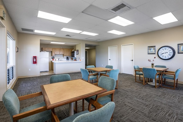 carpeted dining room with a drop ceiling