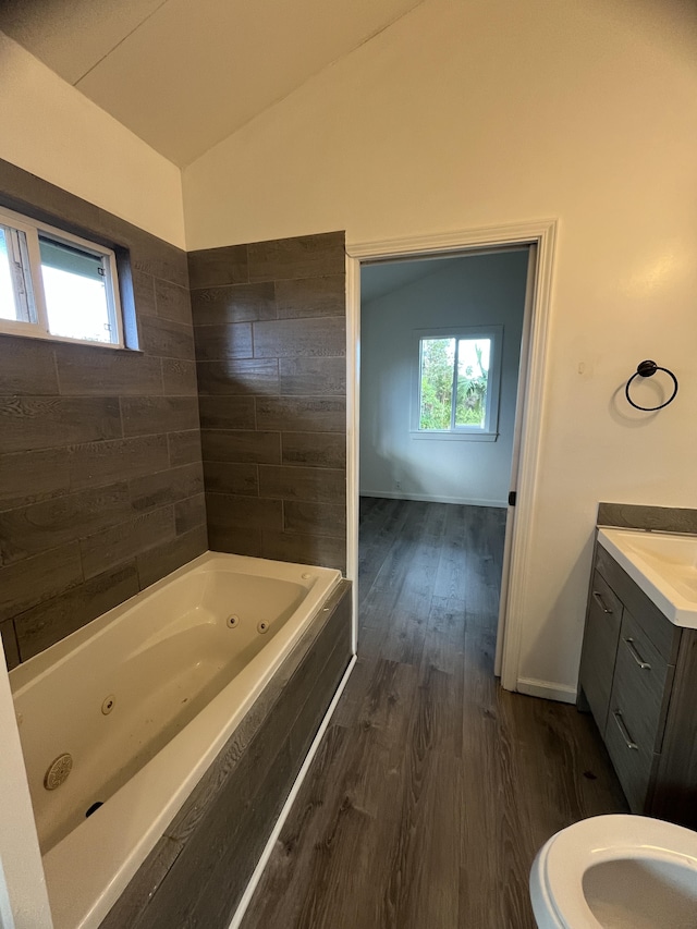 bathroom with hardwood / wood-style floors, a bath, a wealth of natural light, and vaulted ceiling