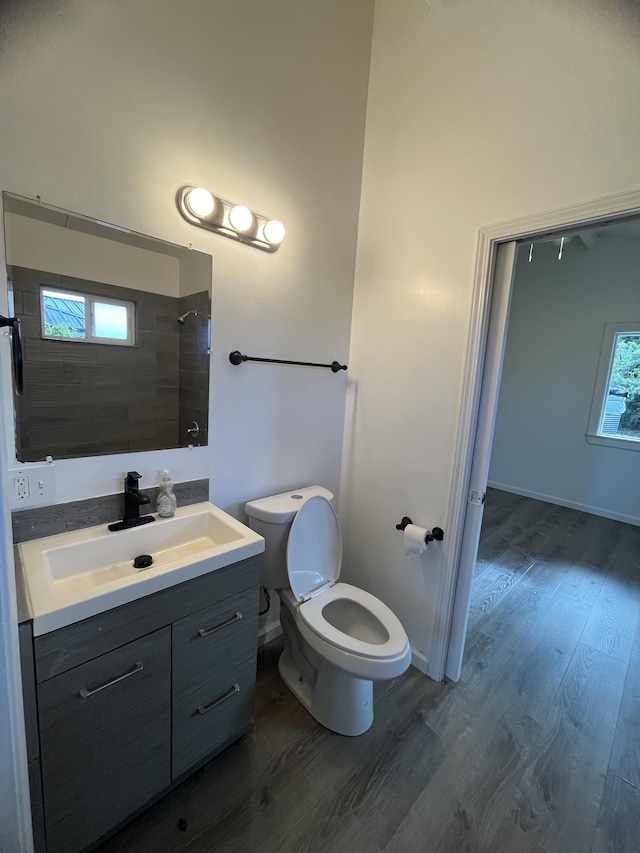 bathroom featuring hardwood / wood-style floors, vanity, toilet, and tiled shower