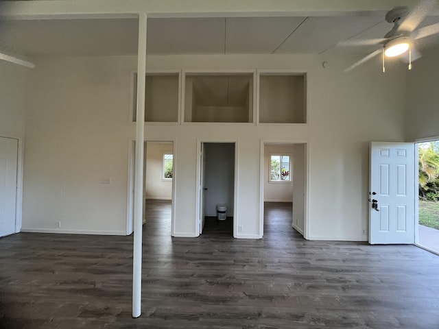 unfurnished room featuring a high ceiling, ceiling fan, and dark wood-type flooring