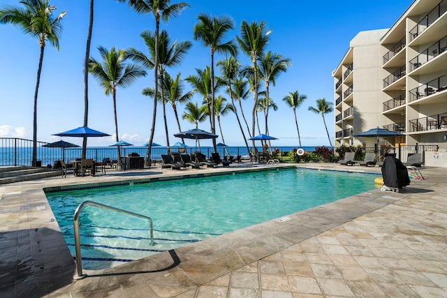 view of swimming pool featuring a water view and a patio