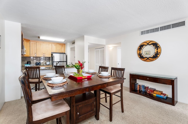 carpeted dining room featuring a textured ceiling