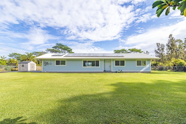 rear view of property with a storage unit, solar panels, and a yard