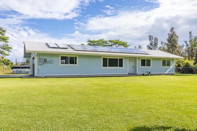 rear view of house with a yard and solar panels