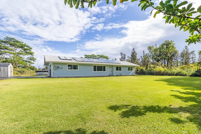 rear view of property featuring a lawn and solar panels