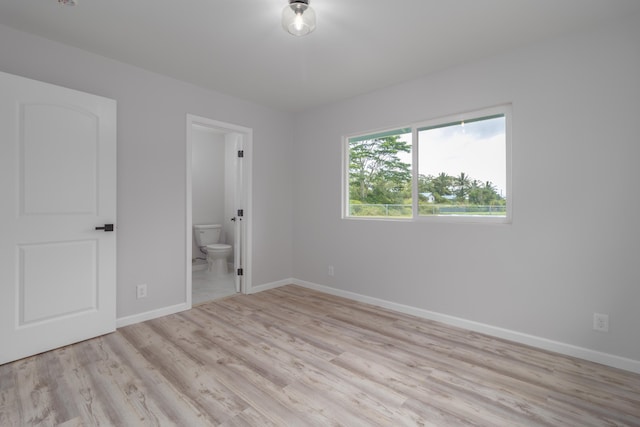 unfurnished bedroom with ensuite bathroom and light hardwood / wood-style flooring