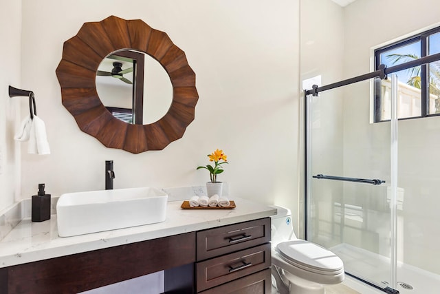 bathroom featuring a shower with shower door, toilet, and vanity