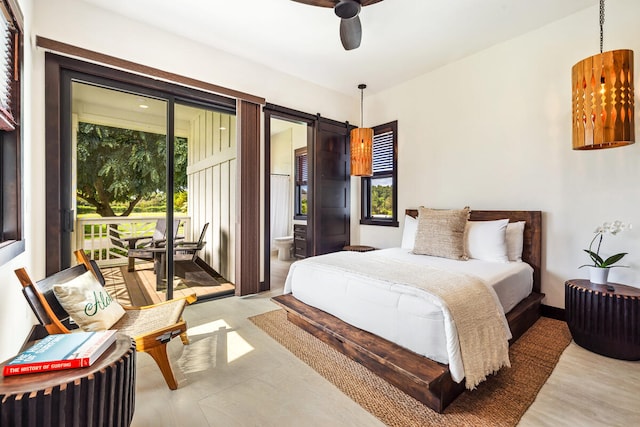 bedroom featuring ceiling fan, ensuite bathroom, access to outside, and a barn door