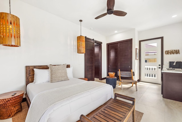 bedroom with ceiling fan, light tile patterned floors, and a barn door