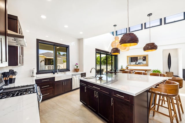 kitchen with pendant lighting, a breakfast bar, sink, appliances with stainless steel finishes, and an island with sink