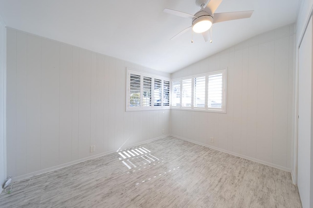 unfurnished room featuring ceiling fan, wooden walls, and lofted ceiling