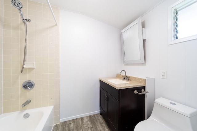 full bathroom with hardwood / wood-style floors, toilet, vanity, and tiled shower / bath combo