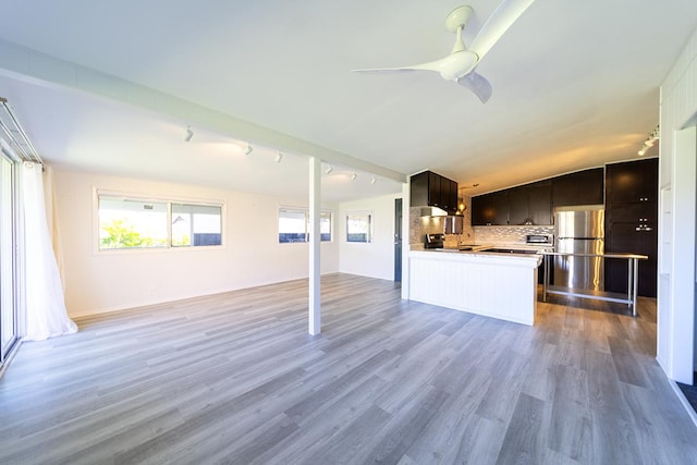 kitchen with decorative backsplash, light hardwood / wood-style floors, stainless steel refrigerator, vaulted ceiling, and ceiling fan