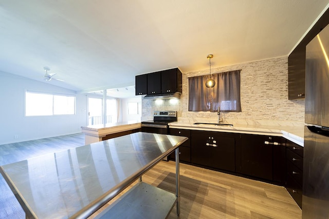 kitchen with appliances with stainless steel finishes, sink, pendant lighting, backsplash, and vaulted ceiling