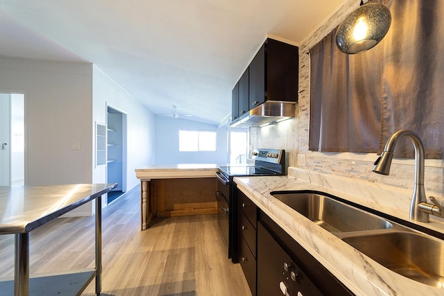 kitchen with vaulted ceiling, sink, backsplash, light wood-type flooring, and range with two ovens