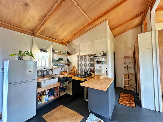 kitchen featuring sink, wooden ceiling, wooden counters, lofted ceiling, and fridge