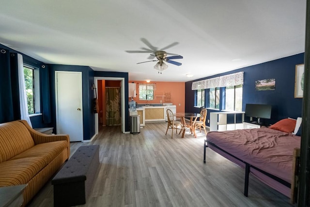 living room featuring wood-type flooring, ceiling fan, and washer / dryer