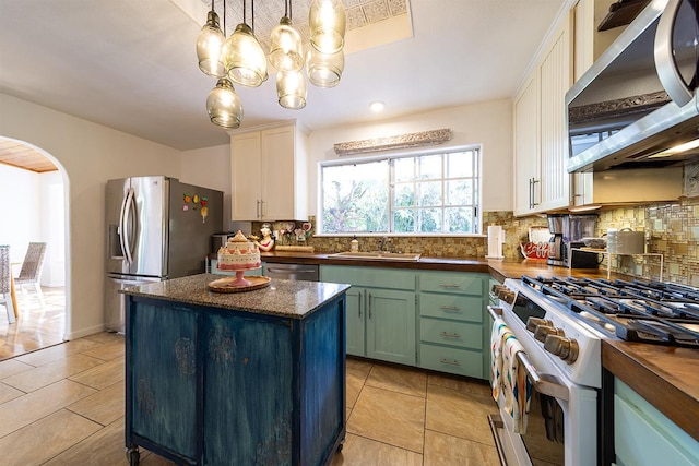 kitchen with wood counters, sink, white cabinetry, pendant lighting, and stainless steel appliances