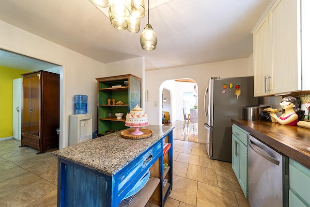 kitchen with white cabinetry, appliances with stainless steel finishes, butcher block countertops, and pendant lighting