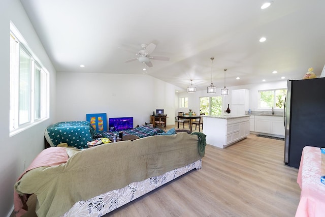 living room with ceiling fan, lofted ceiling, sink, and light wood-type flooring