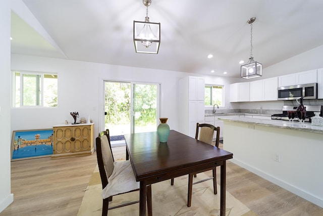 dining area with lofted ceiling, sink, and light wood-type flooring