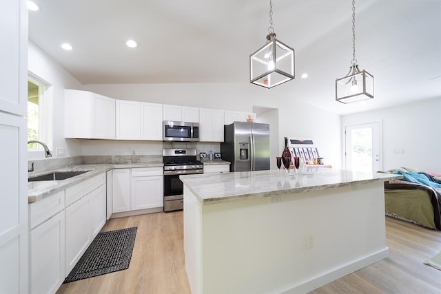 kitchen featuring a kitchen island, white cabinetry, sink, hanging light fixtures, and stainless steel appliances