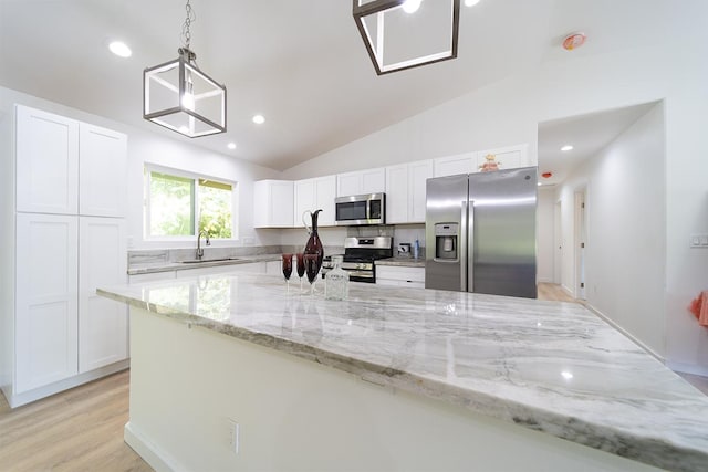 kitchen featuring sink, light stone counters, pendant lighting, stainless steel appliances, and white cabinets