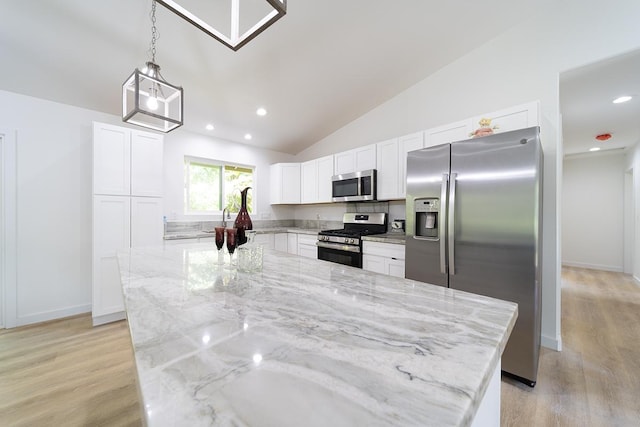 kitchen with pendant lighting, appliances with stainless steel finishes, a center island, light stone countertops, and white cabinets