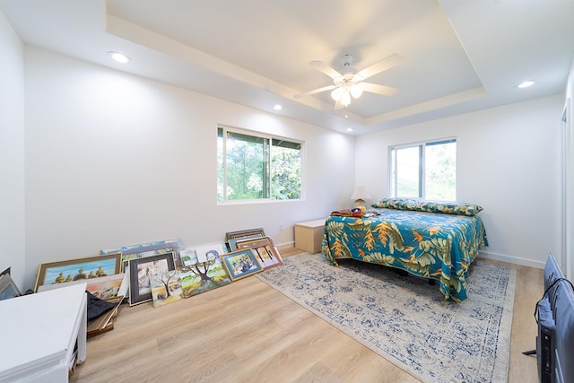 bedroom with hardwood / wood-style flooring, ceiling fan, and a tray ceiling