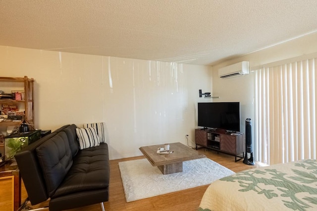 living room featuring a wall unit AC, light hardwood / wood-style flooring, and a textured ceiling