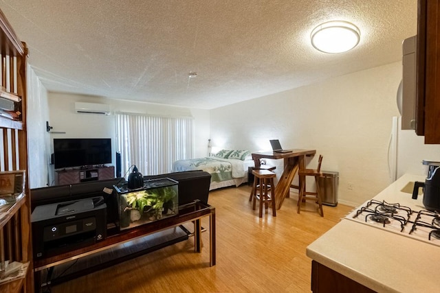 interior space featuring white refrigerator, an AC wall unit, a textured ceiling, and light hardwood / wood-style flooring