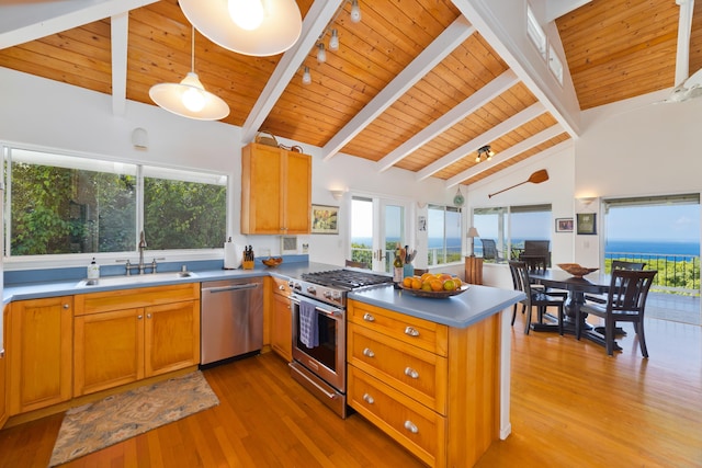 kitchen featuring sink, hanging light fixtures, stainless steel appliances, light hardwood / wood-style floors, and kitchen peninsula