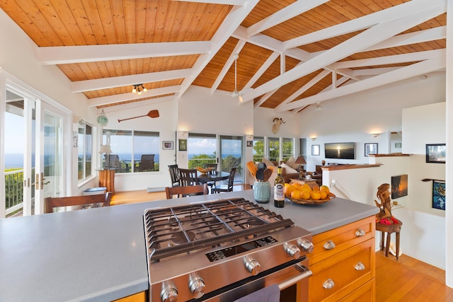 kitchen with light hardwood / wood-style flooring, stainless steel gas range, ceiling fan, lofted ceiling with beams, and wooden ceiling