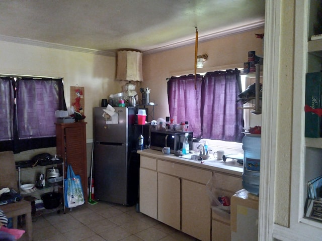 kitchen featuring light tile patterned flooring, stainless steel refrigerator, sink, white cabinets, and crown molding