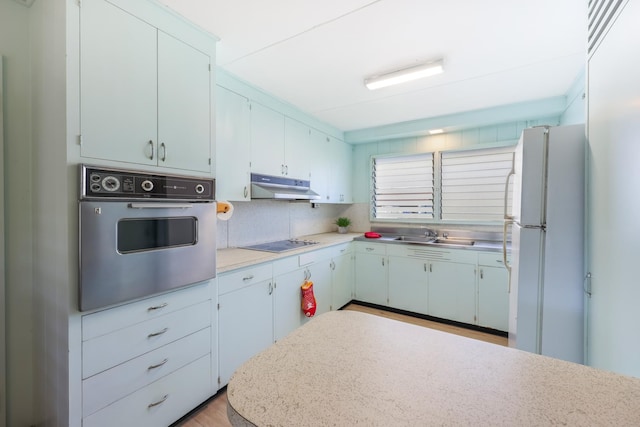 kitchen featuring backsplash, sink, white refrigerator, electric cooktop, and black oven