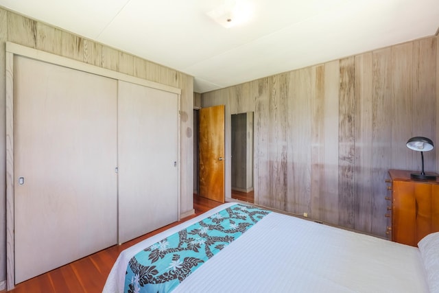 bedroom featuring wood-type flooring, wooden walls, and a closet