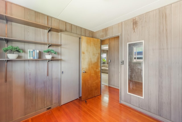 interior space with hardwood / wood-style flooring and wood walls