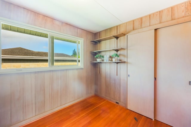 unfurnished room featuring wood-type flooring and wood walls